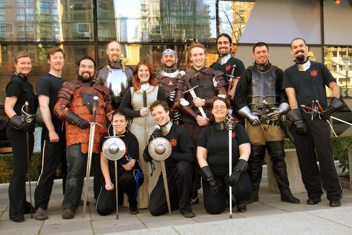 Group of swordfighters posing with longswords, rapiers, and armour at Academie Duello